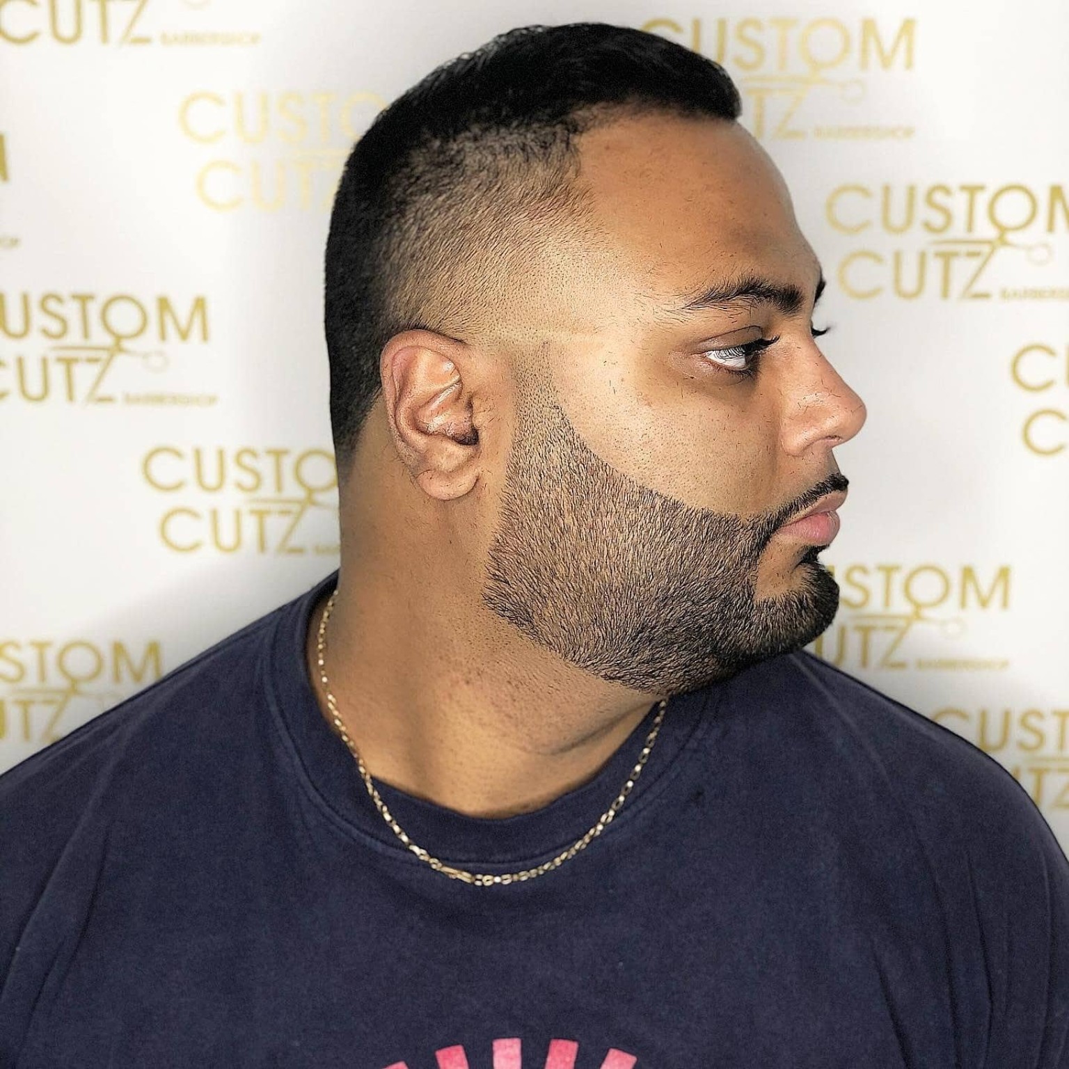 Slicked-back top with a fade and sharply lined beard